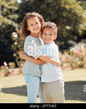 Portrait of a mixed race brother and sister smiling, standing and embracing each other in a garden outside. Hispanic Male and female siblings showing Stock Photo