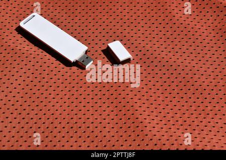 A modern portable USB wi-fi adapter is placed on the red sportswear made of polyester nylon fiber Stock Photo