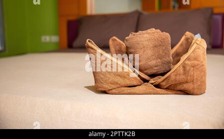 Yellow towel on bed decoration in bedroom interior, Freshly laundered fluffy towels, Towel in hotel room, Beautifully folded toiletries Stock Photo