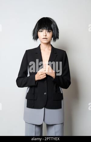 Stylish fashion model in short black wig posing in jacket with deep cut. Stock Photo
