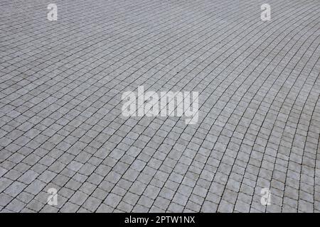 Gray color paving slabs in the pedestrian street sidewalk. Rough cobblestone pattern with many square shaped stones close up Stock Photo
