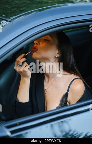 Gorgeous woman applying lipstick in the car Stock Photo