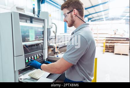 Worker operating a water jet cutting machine by pressing buttons and generally looking good Stock Photo