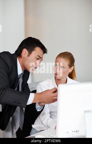 Sharing his business expertise. A helpful businessman aiding a colleague with some work Stock Photo