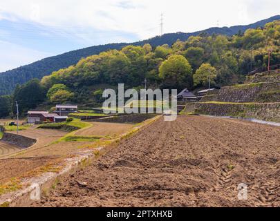 Freshly plowed soil on terraced rice field in traditional Japanese village Stock Photo