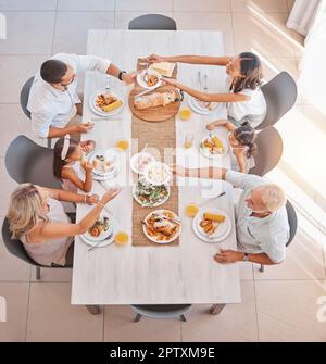 Family, food and lunch with love and care at the dining room table to eat and drink. Group, grandparents and parents with kids eating a delicious meal Stock Photo