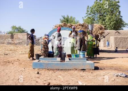 Women and girls collect water from a busy hand-pump well in rural Segou Region, Mali, West Africa. 2022 Mali drought and hunger crisis. Stock Photo