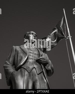A large bronze statue of Mustafa Kamal Ataturk, the founder of modern Turkey, stands next to a flagpole flying the Turkish flag in a square in Side Ol Stock Photo