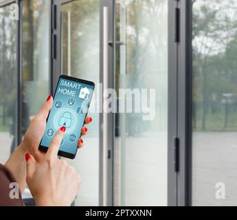 Cropped image of female entering secret key code for getting access and passing building using application on mobile phone, woman pressing buttons on Stock Photo