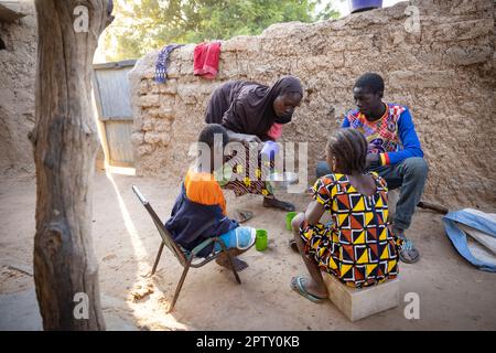 Family eating breakfast meal of cornmeal porridge in Segou Region, Mali, West Africa. 2022 Mali drought and hunger crisis. Stock Photo