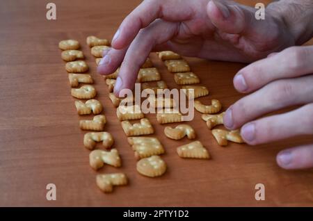 Men's fingers typing on the keyboard, which is composed of salty cracker in the form of letters and numbers. Simulating a computer keyboard using of c Stock Photo