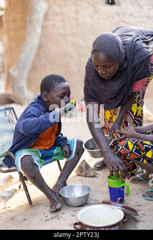 Family eating breakfast meal of cornmeal porridge in Segou Region, Mali, West Africa. 2022 Mali drought and hunger crisis. Stock Photo