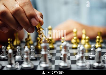 Close up of hands of a business man moving king golden chess to defeat  opponent the chess game is development analysis, strategy, and plan, the  management or leadership concept. 22804709 Stock Photo