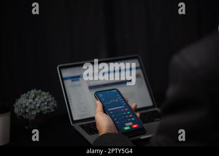 Businessman trader smart phone with graphs analysis candle in office diagrams on screen.Stock exchange market concept.Business finance investment. Stock Photo