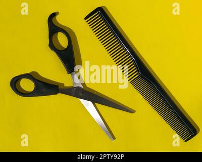 Hairdressing scissors and combs on a yellow background with space for text. Tools of a professional hairdresser. Beauty saloon. Hairdressing equipment Stock Photo