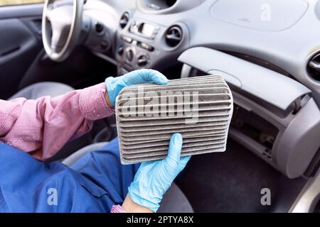 Auto mechanic,wearing protective blue gloves, showing dirty car cabin air  filter. Old car cabin pollen filter replacement Stock Photo - Alamy