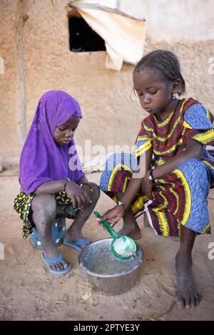 Fulani girls, internally displaced from the conflict in the North, eating morning porridge in Segou Region, Mali, West Africa. 2022 Mali drought and hunger crisis. Stock Photo