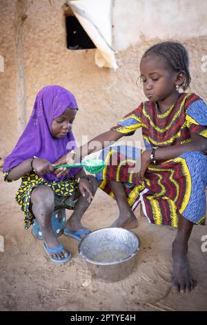 Fulani girls, internally displaced from the conflict in the North, eating morning porridge in Segou Region, Mali, West Africa. 2022 Mali drought and hunger crisis. Stock Photo