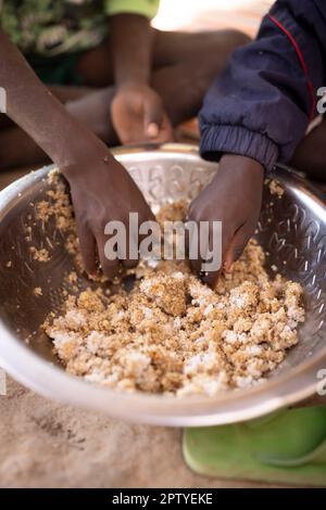 A boy child eats rice out of a communal bowl with his family in Segou Region, Mali, West Africa. 2022 Mali drought and hunger crisis. Stock Photo