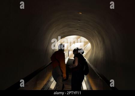 Silhouette of Two Adult Women riding up Escalator Stock Photo