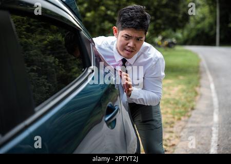 Asian businessman car broken has problems with car down during go to work in morning he pushing out of gas on road at countryside, business man have t Stock Photo