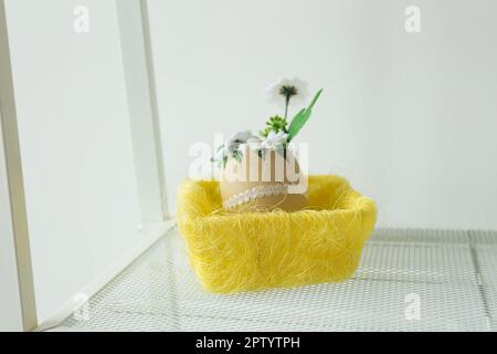 Spring artificial flowers explosion popping out of cracked eggshell on easter basket. Creative Happy Easter and spring or summer, food greeting card. Stock Photo