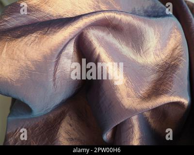 Beautiful fabric - taffeta, gently folded in waves. Crumpled material that looks like silk or brocade. Overflow and color gradient at different lighti Stock Photo