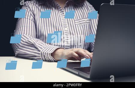 Woman sits at a table and works with a laptop. Document management mystem (DMS). Software for automating archiving and efficient management of informa Stock Photo
