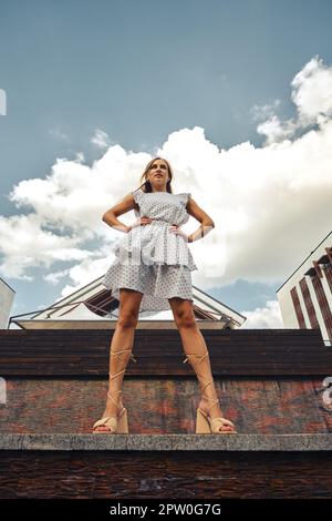 Low angle view portrait of a happy young woman breathing fresh air standing on railing Stock Photo