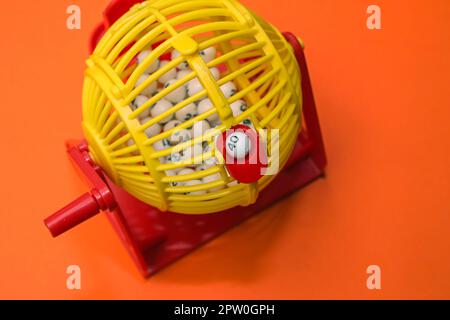 A jolly bright plastic basket with numbers to help with the Lottery, Lotto or just plain Bingo on a simple orange background Stock Photo