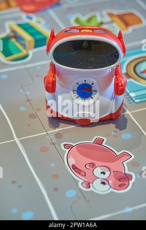 A small red and white robot toy on a colorful playmat featuring cartoon drawings and navigational symbols Stock Photo