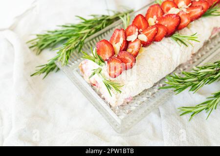 The process of making a meringue roll. Cooking a meringue roll in the kitchen. Meringue roll with strawberries and decorated with rosemary Stock Photo