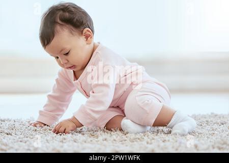 This is soft, like moms hair. an adorable baby girl sitting on the floor at home Stock Photo