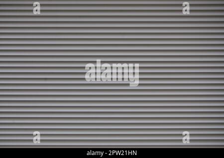 The texture of corrugated metal sheet, white or grey slide door. Old roller shutter texture for background Stock Photo