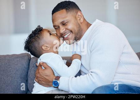 Adorable little boy kissing his dad on the cheek. African american man laughing with his eyes closed while receiving love and affection from his son. Stock Photo