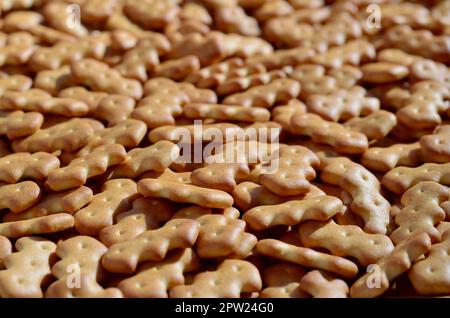 A huge bunch of salted biscuits of small sizes as a closed pattern or texture. A large amount of salted cracker in golden yellow tones Stock Photo