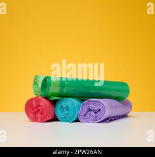 Stack of disposable plastic trash can bags on a yellow background Stock Photo