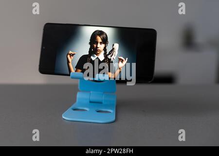 Smartphone stands on a stand with Wednesday screen Stock Photo