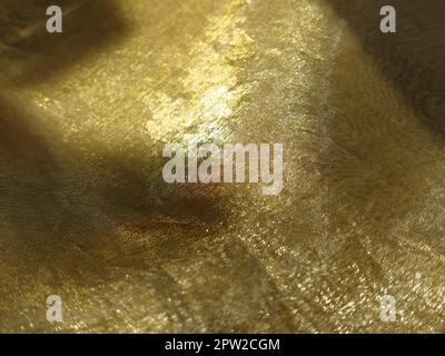 Curtain loops. Beautiful gold fabric. Organza in yellow, orange, beige and brown shades. Pleats in the fabric. Shiny gradient under the light. Folded Stock Photo