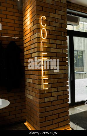 Coffee neon sign emblem in neon style on brick wall background. Stock Photo
