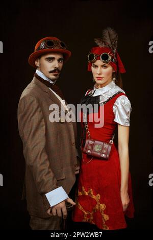 Low key portrait of a couple in steampunk clothes, glasses and cane Stock Photo