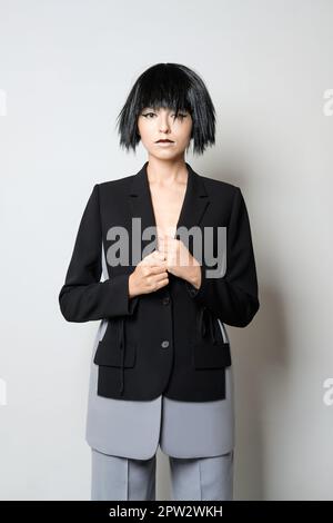 Stylish fashion model in short black wig posing in jacket with deep cut. Stock Photo