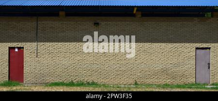 Texture of brick wall from relief stones under bright sunlight with two metal doors Stock Photo