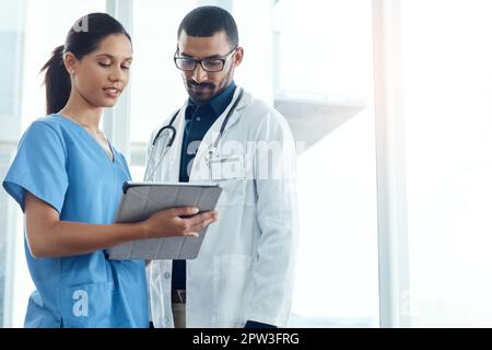 It takes two to make this diagnosis. two young doctors using a digital tablet in a modern hospital. Stock Photo
