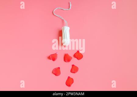 Hygienic cotton tampon and flower petals on pink background. Feminine menstrual hygiene product. Womens health concept. Copy space. Stock Photo