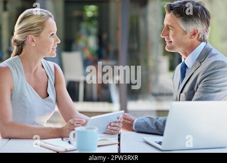 They turn ideas into success. two mature businesspeople talking together of a tablet and laptop Stock Photo