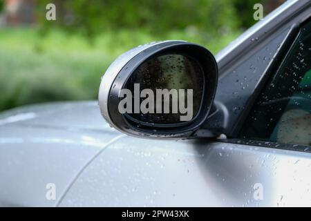 Close up side view wing mirror at car after washing car or raining with isolated green background. Car mirror to see behind of car. Stock Photo