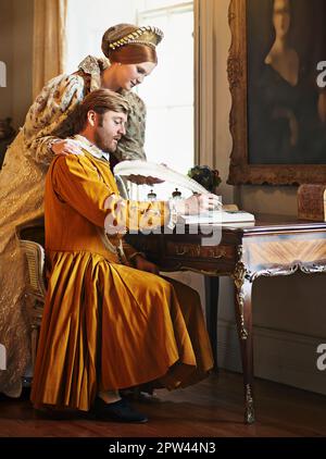 We must dispatch this letter quickly. an aristocratic couple writing a letter at an ornate table Stock Photo