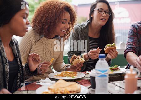 This is the best place in town. a friends eating burgers outdoors Stock Photo