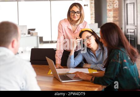 Colleagues in casual clothes browsing presentation on netbook and thinking while working on project together Stock Photo